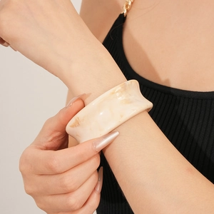 Close-up of resin cuff bracelet with beige marble texture worn by a fashion model