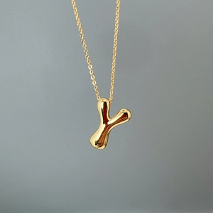 Close-up of polished gold-finished letter Y pendant on a delicate chain necklace