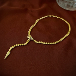 Detailed close-up of gold-plated snake-style Y-necklace with conical pendant charm