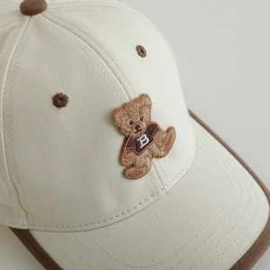 Gros plan de la broderie ours et du tissu en coton sur la casquette pour enfants