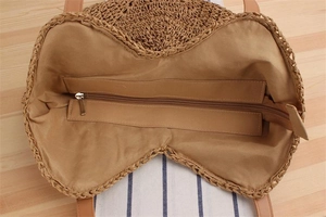 Close-up of woven straw bag with fabric lining and secure metal zipper closure