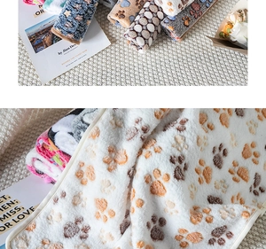 Close-up of soft flannel pet blanket with cute paw prints and rolled-up fabric texture