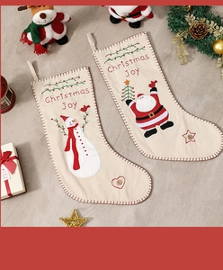 Detail of Christmas Joy embroidered stockings with snowman and Santa on light wood