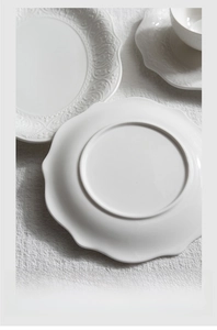 Detail of unglazed bottom edge for anti-slip on embossed white ceramic dinner plate