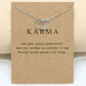 Detailed view of silver interlocking circles Karma necklace on a brown kraft paper card