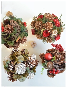 Detailed top view of four festive pine cone ornaments with golden berries and green leaves