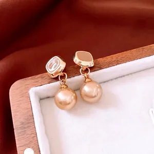 Eleganti orecchini a perno quadrati dorati con perle champagne e smalto marrone