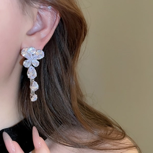 Dettaglio di orecchini pendenti in argento con cristalli di zircone su una modella