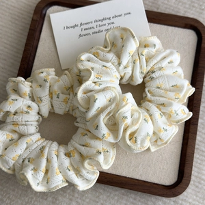 Floral cotton lace scrunchies 2-piece set in white and yellow on a wooden tray
