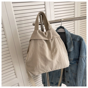 Detailed view of cream nylon tote bag hanging with a denim jacket in a casual setting