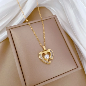 Detail of gold heart pendant with round white pearl and zircon on silk fabric