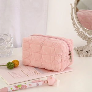 Macro view of pink plush makeup bag featuring heart quilted pattern and zipper detail