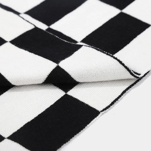 Gros plan sur la texture tricotée en damier montrant des coutures noires et blanches
