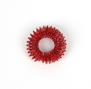 Detail of a red metallic spring finger massage ring for acupressure therapy