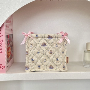 Quilted fabric storage basket with cartoon rabbit and floral print on white shelf