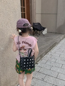 Detail of a child wearing a black woven bucket bag and pink shirt for summer outdoor style