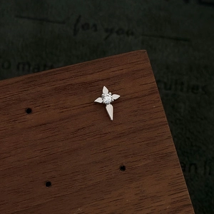 Detailed macro view of a silver star-shaped earring with a central zircon on wood