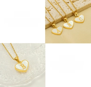 Detail of heart initial pendant with white shell inlay and polished gold finish