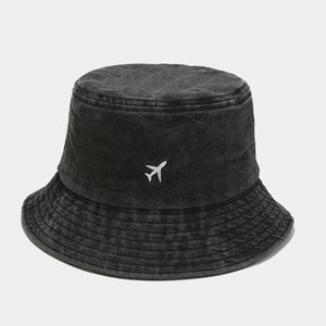 Détail de la broderie avion blanc sur chapeau bob en coton noir délavé avec œillets