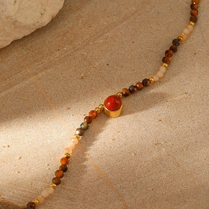Macro detail of Bohemian natural stone necklace with tiger eye and red agate beads