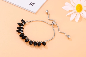 Detail of adjustable black beaded bracelet with silver sliding clasp and drop charm