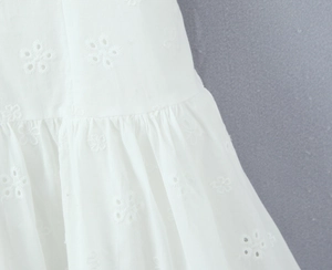 Close-up of white cotton fabric with delicate hollow floral eyelet embroidery details