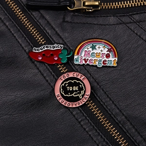 Close-up of three neurospicy enamel pins on a black leather jacket showcasing colorful designs