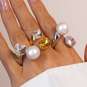 Detail of chunky rings featuring large faceted crystals and pearls on model hands