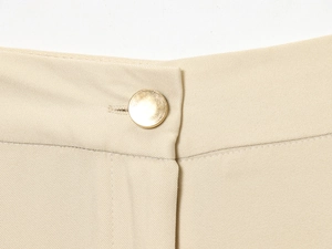 Vue macro de la taille en sergé kaki avec un bouton métallique doré mat de qualité
