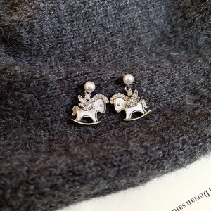 Detailed view of rocking horse earrings with pearls and micro-pave wings on grey sweater