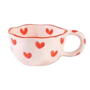 Handcrafted wavy ceramic mug with red hearts and rim in a minimalist cream finish