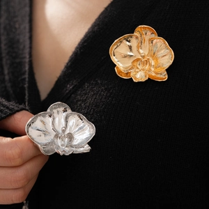 Detailed macro view of orchid shaped metal brooches in gold and silver finish