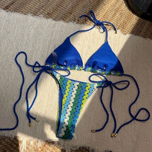 Détail du bikini au crochet bleu avec broderie ondulée et embouts dorés de cordon