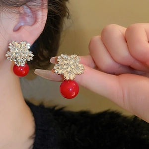 Macro detail of gold snowflake earrings with red pearl drop and shimmering crystals