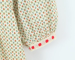Detail van de pofmouw manchet met bloemenpatroon en rode gestipte kanten afwerking