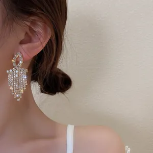 Macro shot of 925 silver needle drop earrings with sparkling rhinestones and tassels
