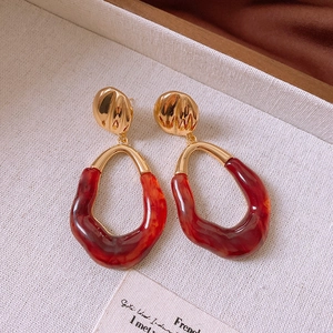 Close-up of vintage irregular amber resin and gold metal dangle earrings on beige tray