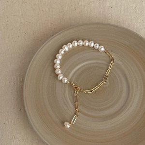 Close-up of Baroque pearl bracelet with gold metal chain links and lobster clasp on ceramic
