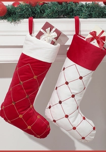 Detail von roten und weißen Samt-Weihnachtssocken mit Rautenstickerei am Kamin hängend