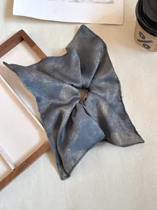 Detailed shot of dark grey oversized scrunchie with metallic marble texture and silk finish