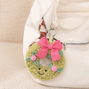Detail of green plush wreath charm with pink bow hanging on a white canvas bag