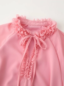 Detail of pink chiffon blouse neckline featuring ruffled collar and V-neck tie-up design