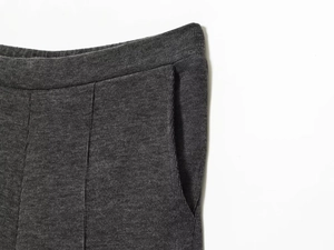 Detail view of elastic waistband and side pocket on dark gray knitted casual trousers