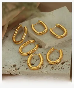 Detailed set of three geometric gold-plated titanium steel hoop earrings on stone