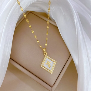 Macro detail of gold necklace with diamond-set rhombus shell pendant and fleur-de-lis motif