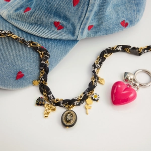 Gros plan détaillé du collier vintage cœur fleur avec emblème floral doré et breloques