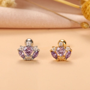 Gros plan de boucles d'oreilles couronne en or et argent avec zircons violets en cœur