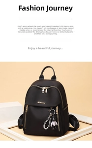 Detail of black nylon backpack with golden double zippers and a cute bear keychain charm