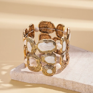 Detail of irregular geometric gold cuff bracelet with marble enamel inlays on stone surface
