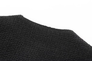 Close-up of black tweed fabric texture and woven pattern detail on women's jacket